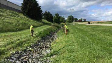 Two R+R employees maintaining vegetation in a grassed swale