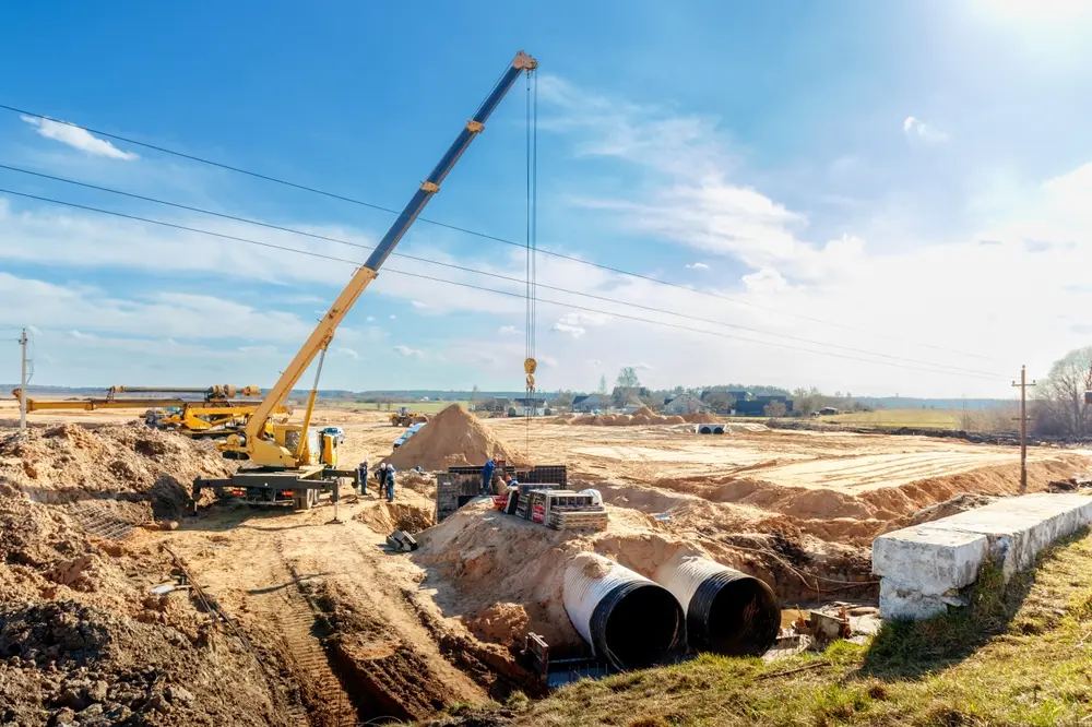 Connecting a trench drain to a concrete manhole structure at construction site. Concrete pile in formwork frame for construct stormwater and underground utilities, pump stations, sewers pipes.